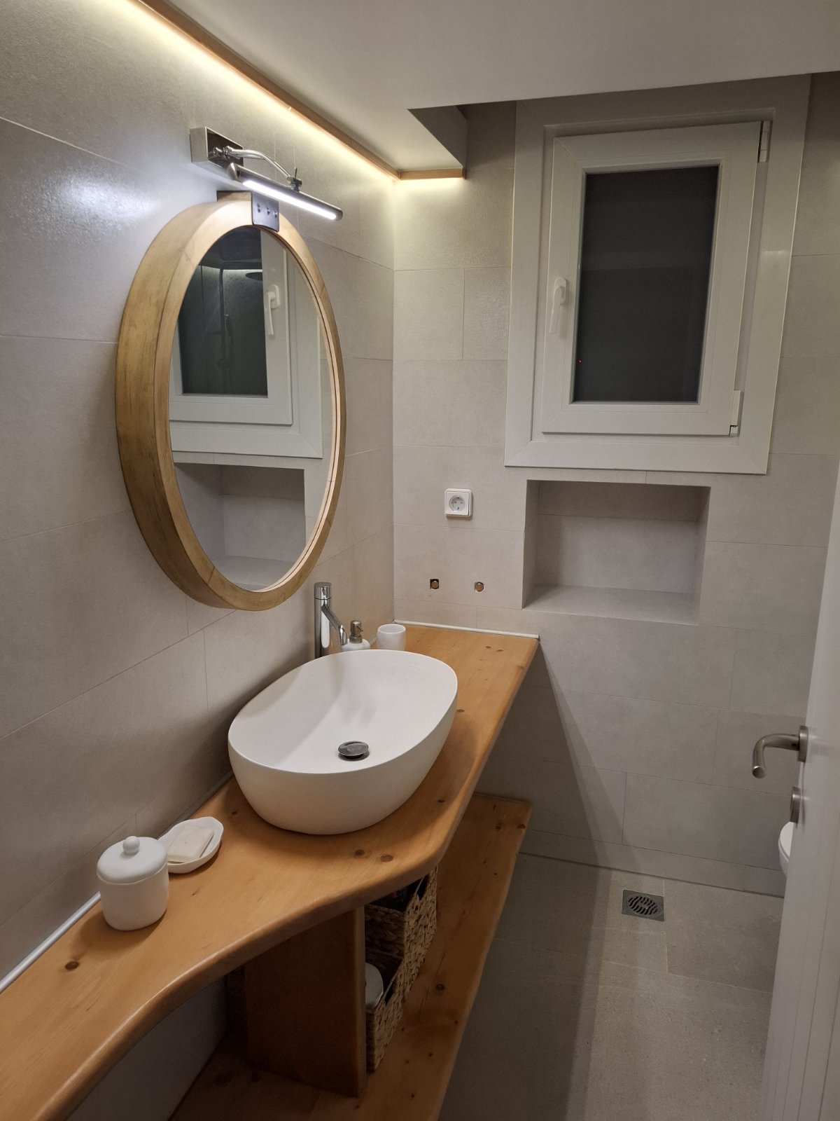 Minimal en-suite bathroom with wooden vanity and concealed lighting at Villa Manesi